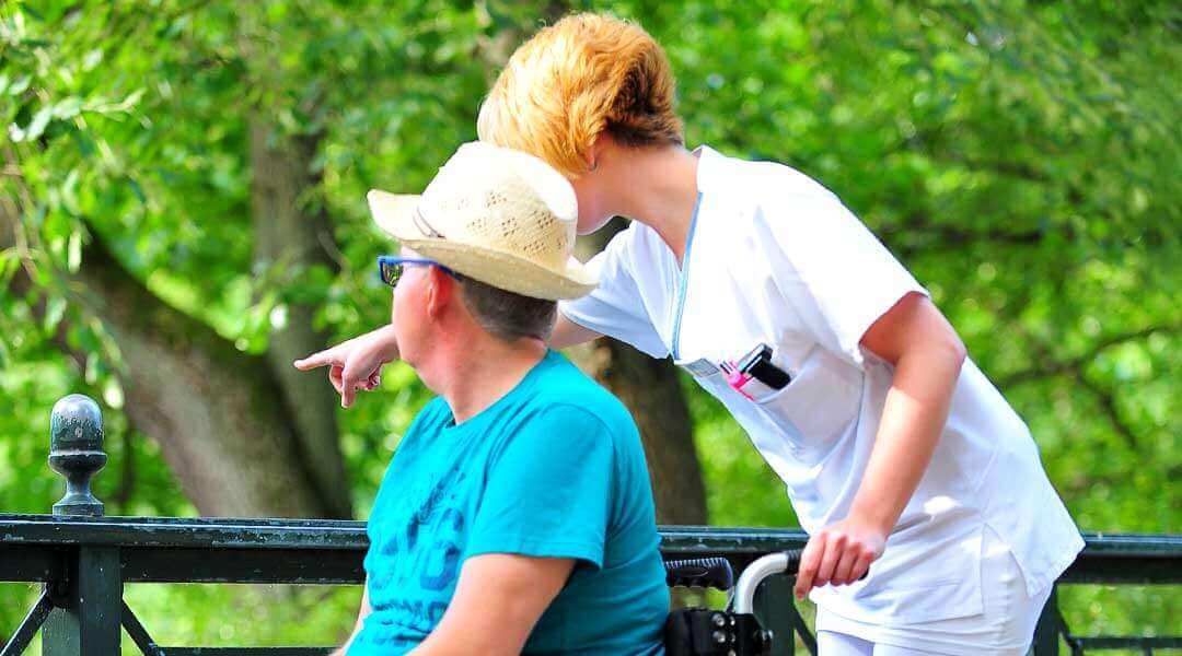 Pflegerin und Patient beim Spaziergang am See