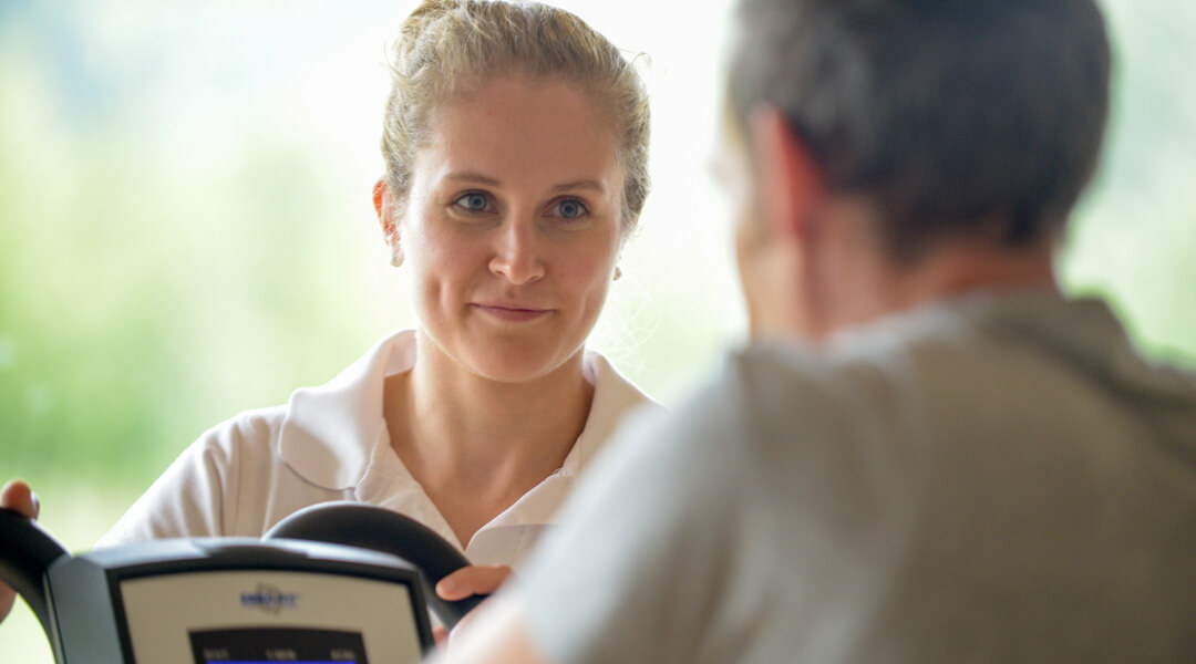 Therapeutin erklärt Ergometer in der Sporttherapie der Caspar Heinrich Klinik